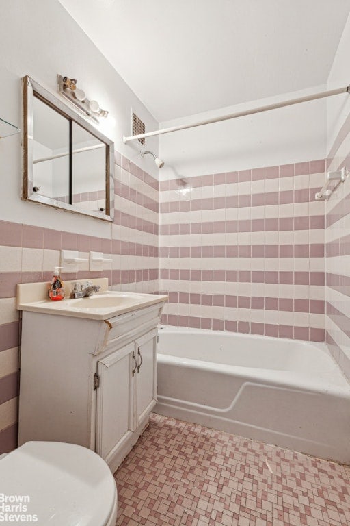 bathroom featuring toilet, tub / shower combination, vanity, and tile walls