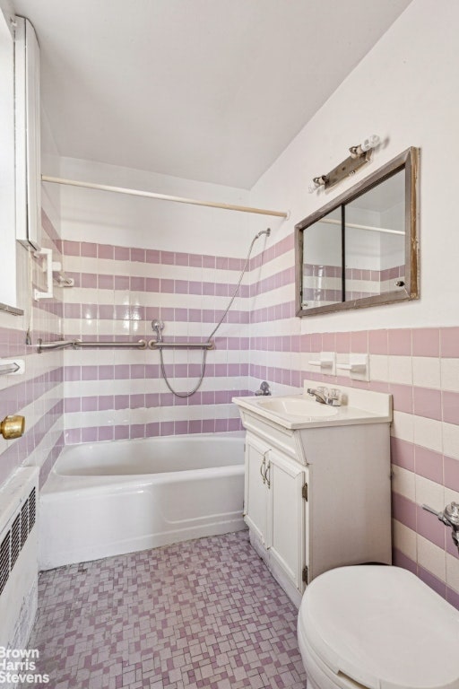 full bath featuring tile walls, radiator, toilet, vanity, and shower / tub combination