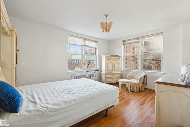 bedroom featuring radiator, light wood-style flooring, and an inviting chandelier