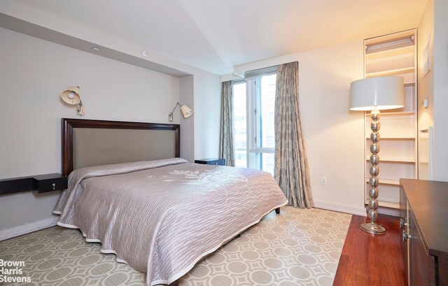 60 E 55th St Unit 15D, New York City, NY 10022 - bedroom featuring baseboards and wood finished floors
