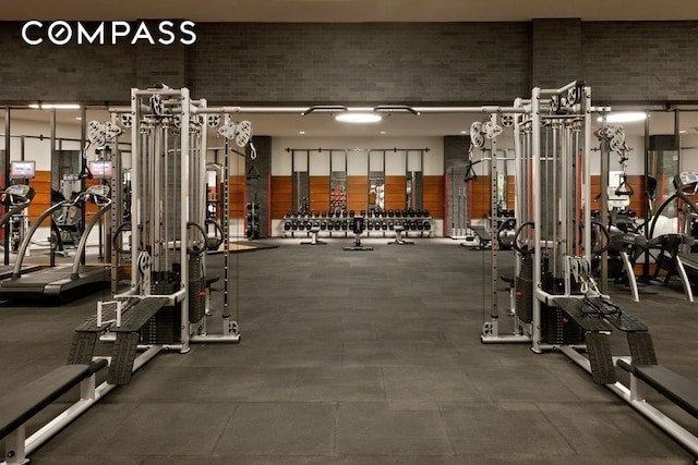 exercise room with brick wall and a high ceiling