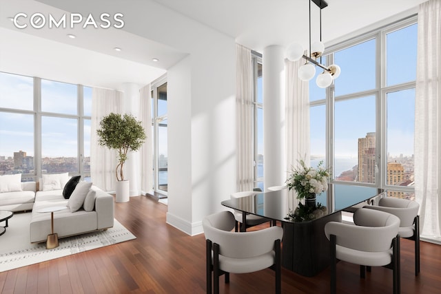 dining room with a view of city, a wall of windows, dark wood finished floors, and a chandelier