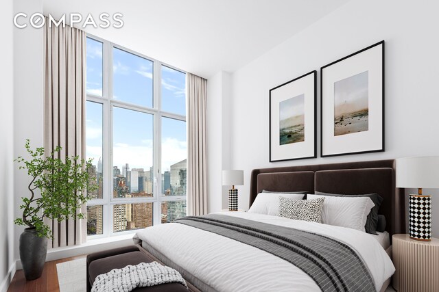 bedroom featuring multiple windows, wood finished floors, a skyline view, and a wall of windows