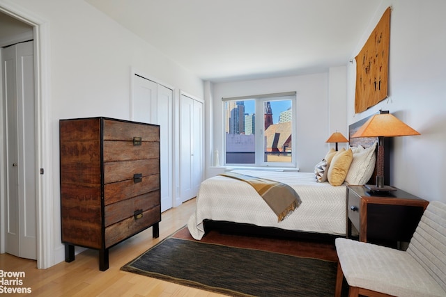 bedroom with light wood-style floors and multiple closets