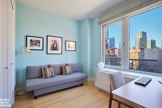 office with baseboards, light wood-style floors, and a city view