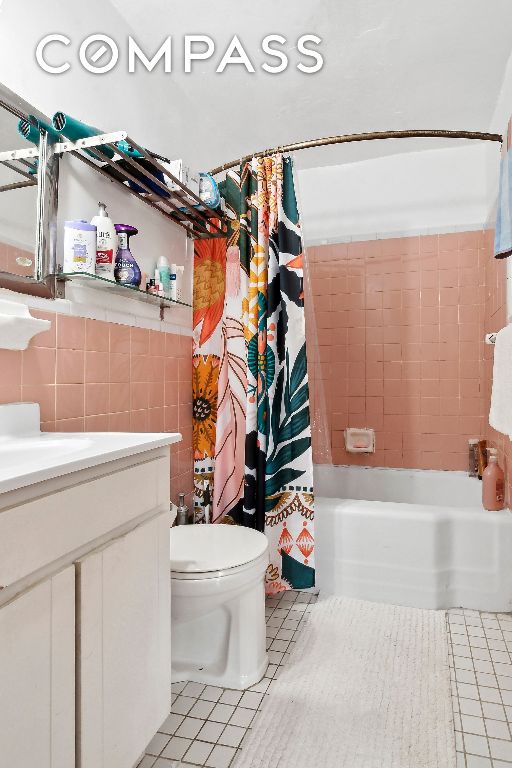 full bathroom with toilet, tile patterned floors, vanity, tile walls, and shower / tub combo with curtain