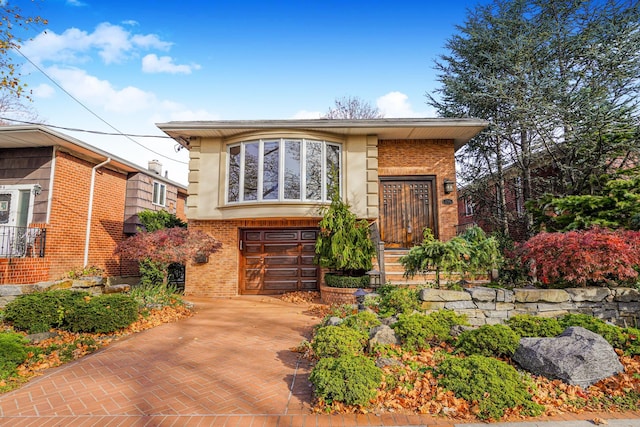 view of front of property with brick siding, decorative driveway, an attached garage, and stucco siding