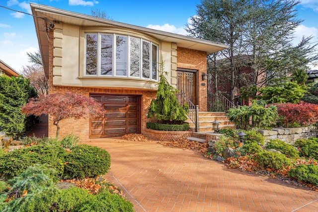 view of front of property with stucco siding, decorative driveway, and brick siding