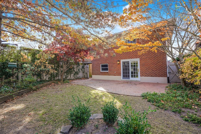 rear view of property with a patio, brick siding, fence, a lawn, and a gate