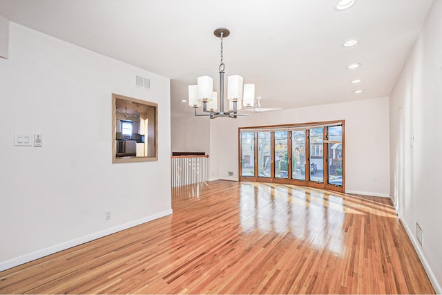 interior space featuring baseboards, visible vents, a notable chandelier, and light wood finished floors