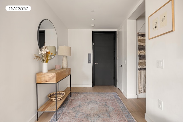 corridor with baseboards, visible vents, and wood finished floors