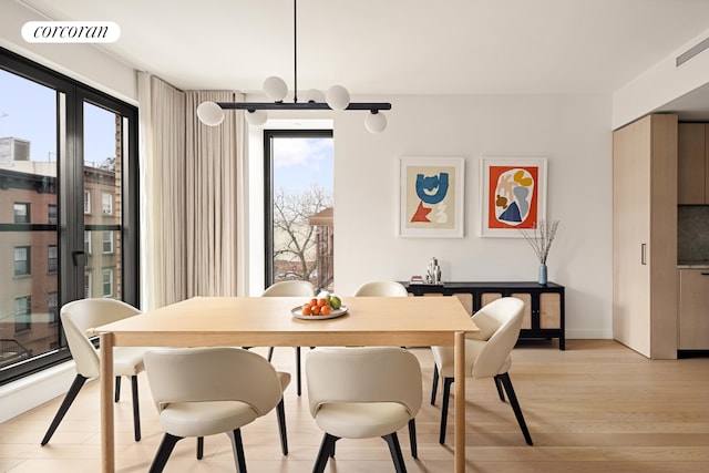 dining room with light wood finished floors, visible vents, and an inviting chandelier