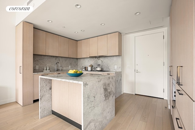 kitchen with a center island, light wood finished floors, visible vents, decorative backsplash, and modern cabinets