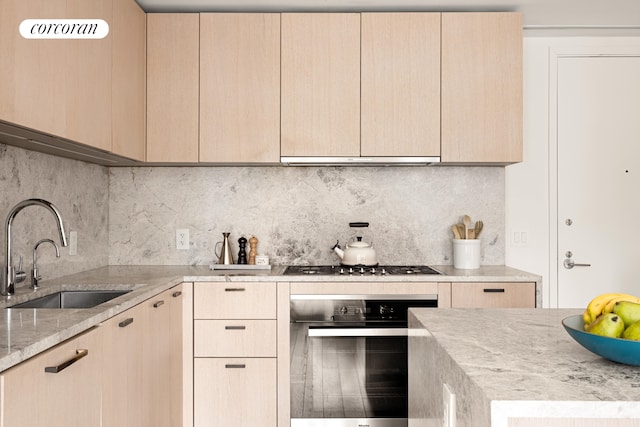 kitchen featuring light brown cabinets, appliances with stainless steel finishes, and a sink