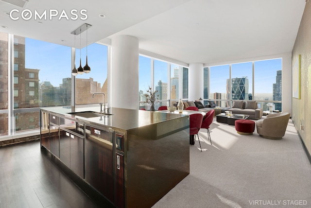 kitchen featuring a sink, expansive windows, a view of city, and a center island with sink