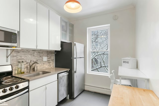 kitchen featuring a sink, white cabinetry, appliances with stainless steel finishes, tasteful backsplash, and crown molding