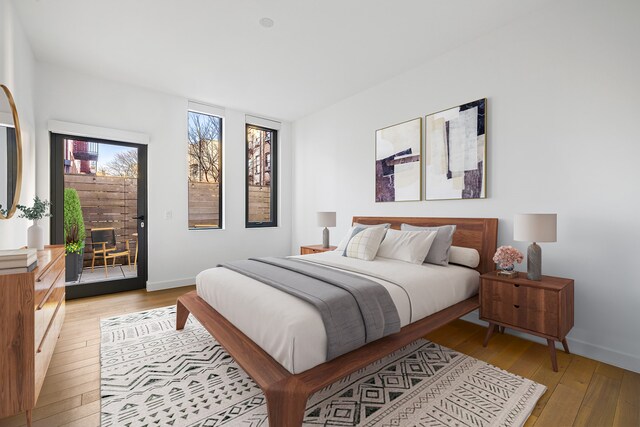 150 Rivington St Unit 2H, New York City, NY 10002 - bedroom with light wood-style flooring, access to exterior, a fireplace, and baseboards