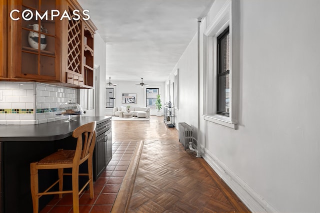 kitchen featuring tasteful backsplash, radiator, a ceiling fan, open floor plan, and baseboards