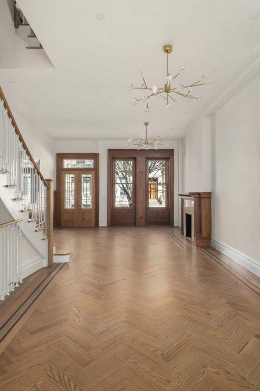 unfurnished living room with a high end fireplace, baseboards, stairs, french doors, and an inviting chandelier