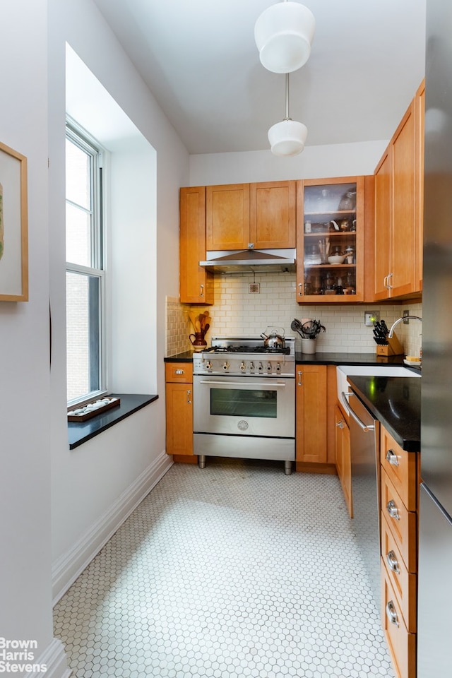 kitchen featuring baseboards, glass insert cabinets, under cabinet range hood, appliances with stainless steel finishes, and tasteful backsplash