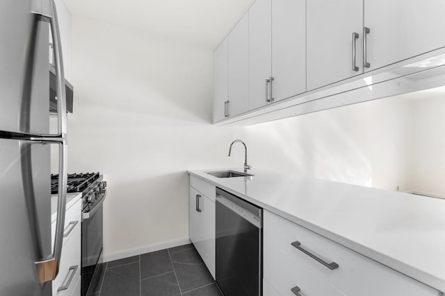 kitchen with appliances with stainless steel finishes, light countertops, white cabinetry, and a sink