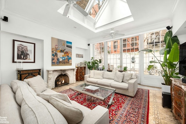 living area with a ceiling fan, a skylight, a high end fireplace, and crown molding