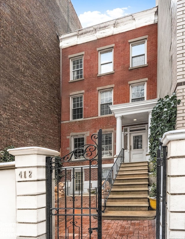 townhome / multi-family property with a gate and brick siding