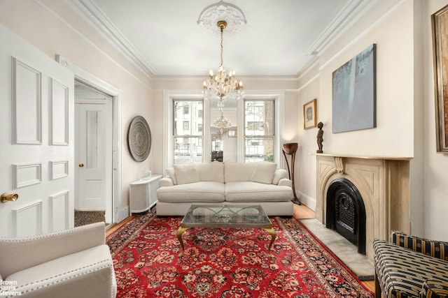 living area featuring light wood finished floors, baseboards, ornamental molding, an inviting chandelier, and a fireplace