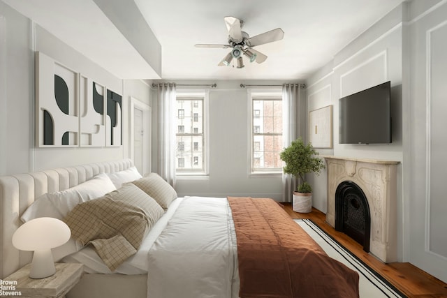 bedroom with a fireplace, a ceiling fan, and light wood-type flooring