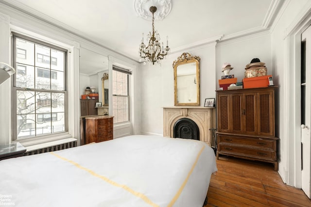bedroom with ornamental molding, hardwood / wood-style flooring, and a chandelier