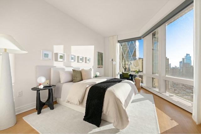 bedroom featuring lofted ceiling, access to exterior, baseboards, and wood finished floors