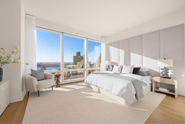 bedroom with a view of city and light wood finished floors