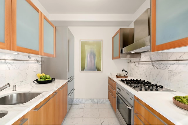 kitchen with stainless steel appliances, a sink, marble finish floor, wall chimney range hood, and glass insert cabinets