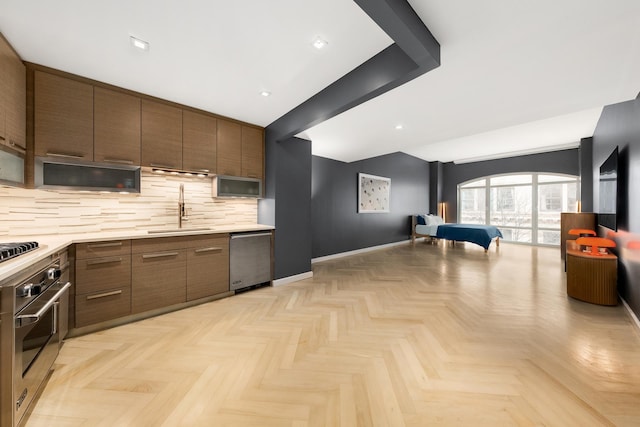 kitchen with stainless steel appliances, a sink, light countertops, and decorative backsplash