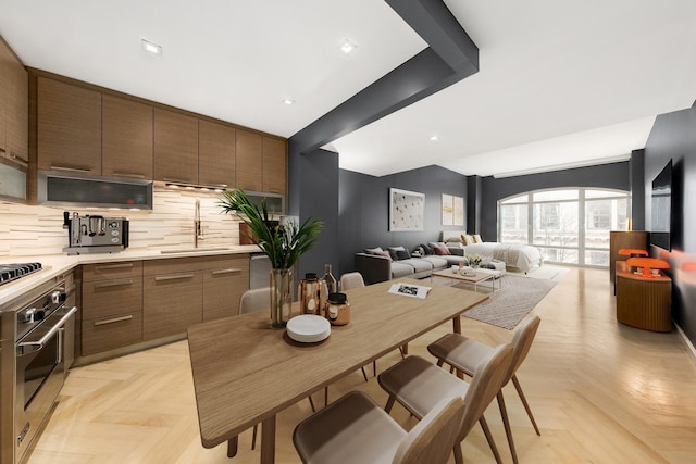 kitchen with decorative backsplash, modern cabinets, a sink, light countertops, and open floor plan