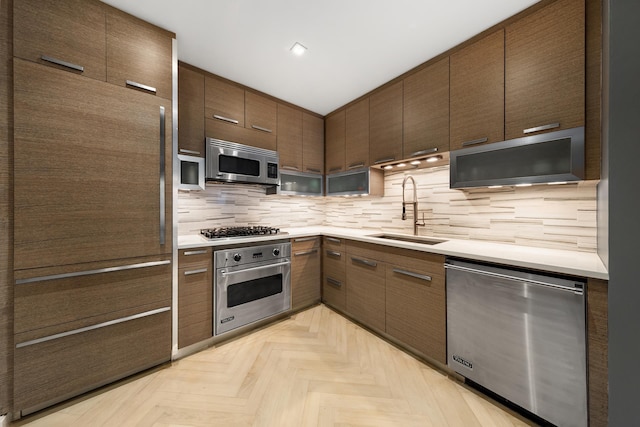 kitchen with modern cabinets, a sink, stainless steel appliances, light countertops, and backsplash