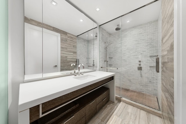 full bath featuring a shower stall, tile walls, and vanity