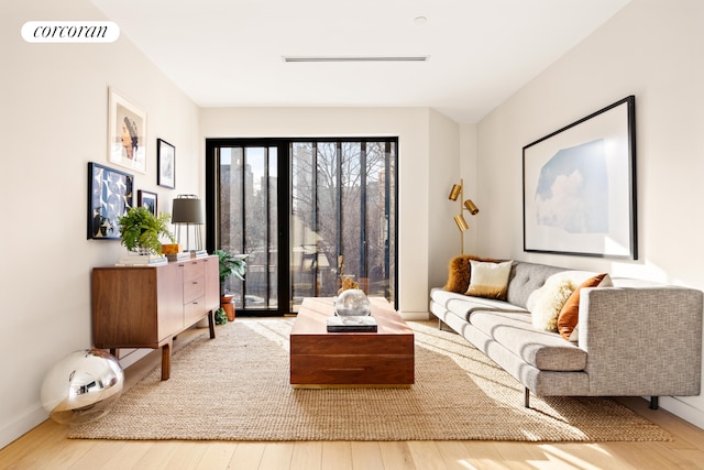 living room with wood finished floors, visible vents, and baseboards