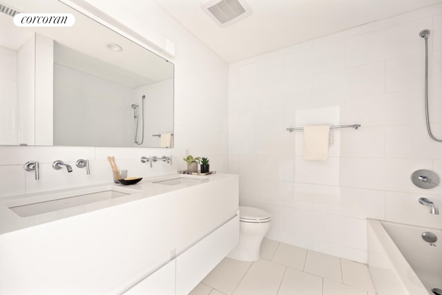 bathroom featuring tile walls, tile patterned flooring, toilet, shower / washtub combination, and double vanity