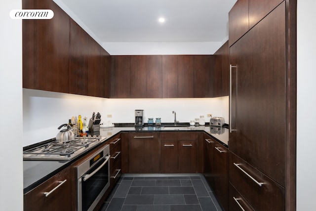 kitchen with appliances with stainless steel finishes, a sink, dark countertops, and modern cabinets