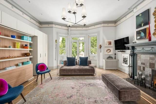 sitting room with ornamental molding, a tiled fireplace, and a notable chandelier