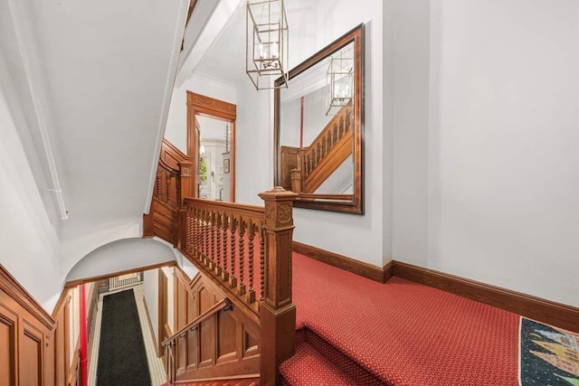 stairway with a notable chandelier, carpet, and baseboards