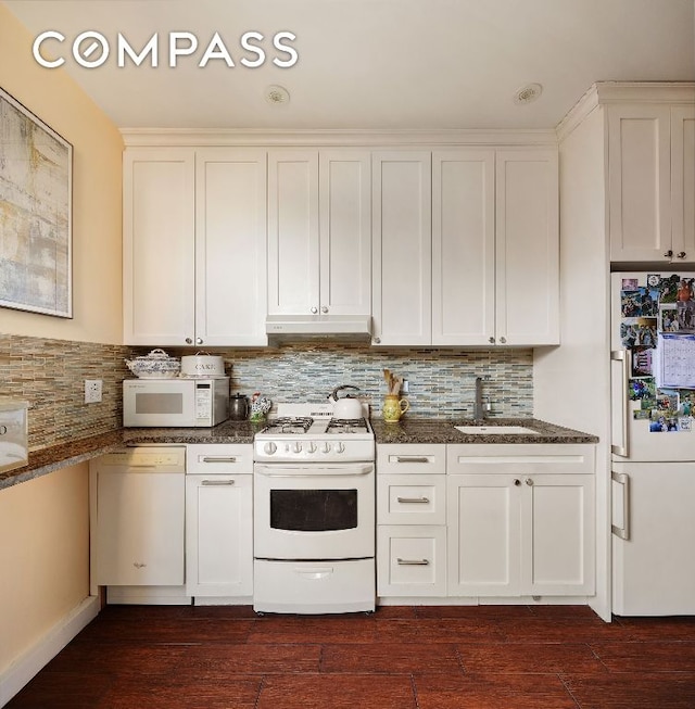 kitchen featuring under cabinet range hood, white appliances, a sink, white cabinets, and tasteful backsplash