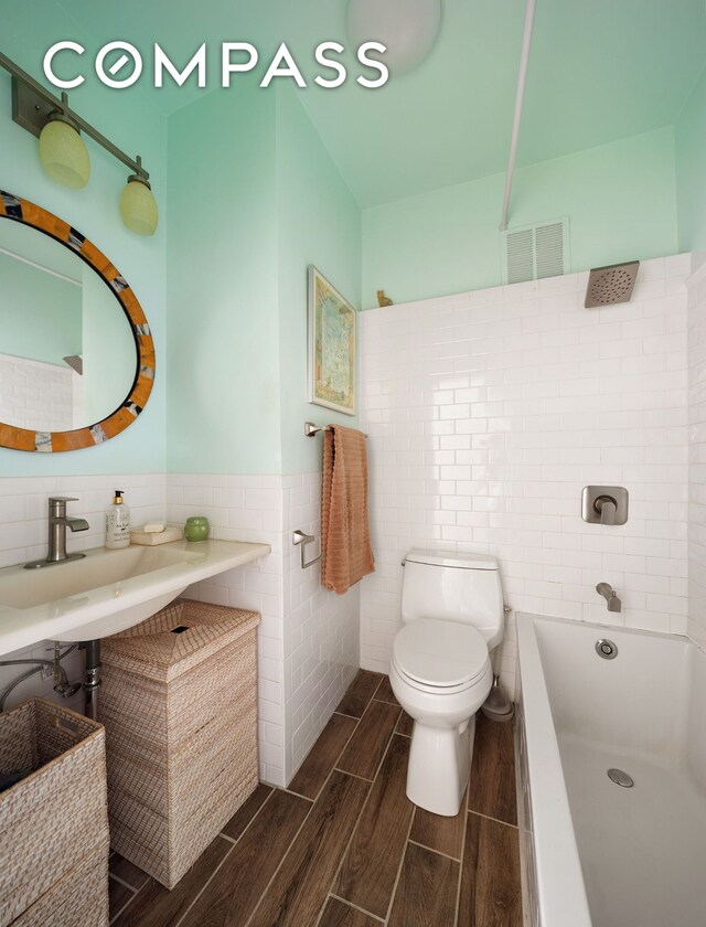 8 Bethune St Unit 14, New York City, NY 10014 - full bath featuring tile walls, toilet, wood finished floors, a sink, and shower / bathtub combination