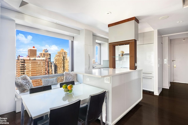 kitchen with modern cabinets, dark wood-type flooring, light countertops, a breakfast bar area, and recessed lighting
