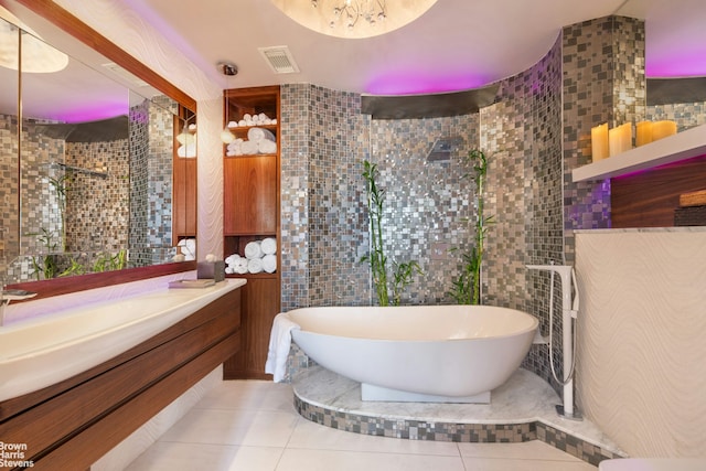 bathroom featuring tile walls, tile patterned floors, a freestanding tub, vanity, and tiled shower