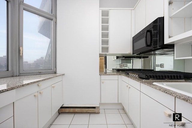 kitchen featuring white cabinetry, black microwave, open shelves, and light stone counters