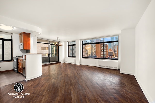 unfurnished living room featuring a chandelier, baseboards, and radiator heating unit