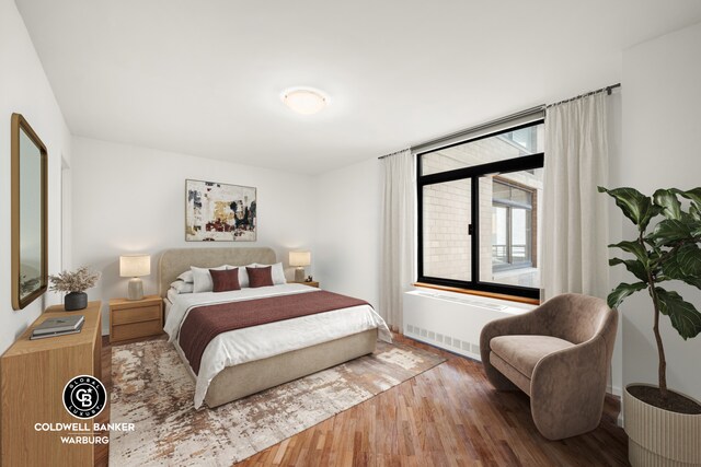 bedroom featuring wood finished floors and radiator heating unit