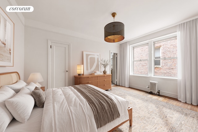 bedroom with visible vents, radiator heating unit, and light wood-style flooring